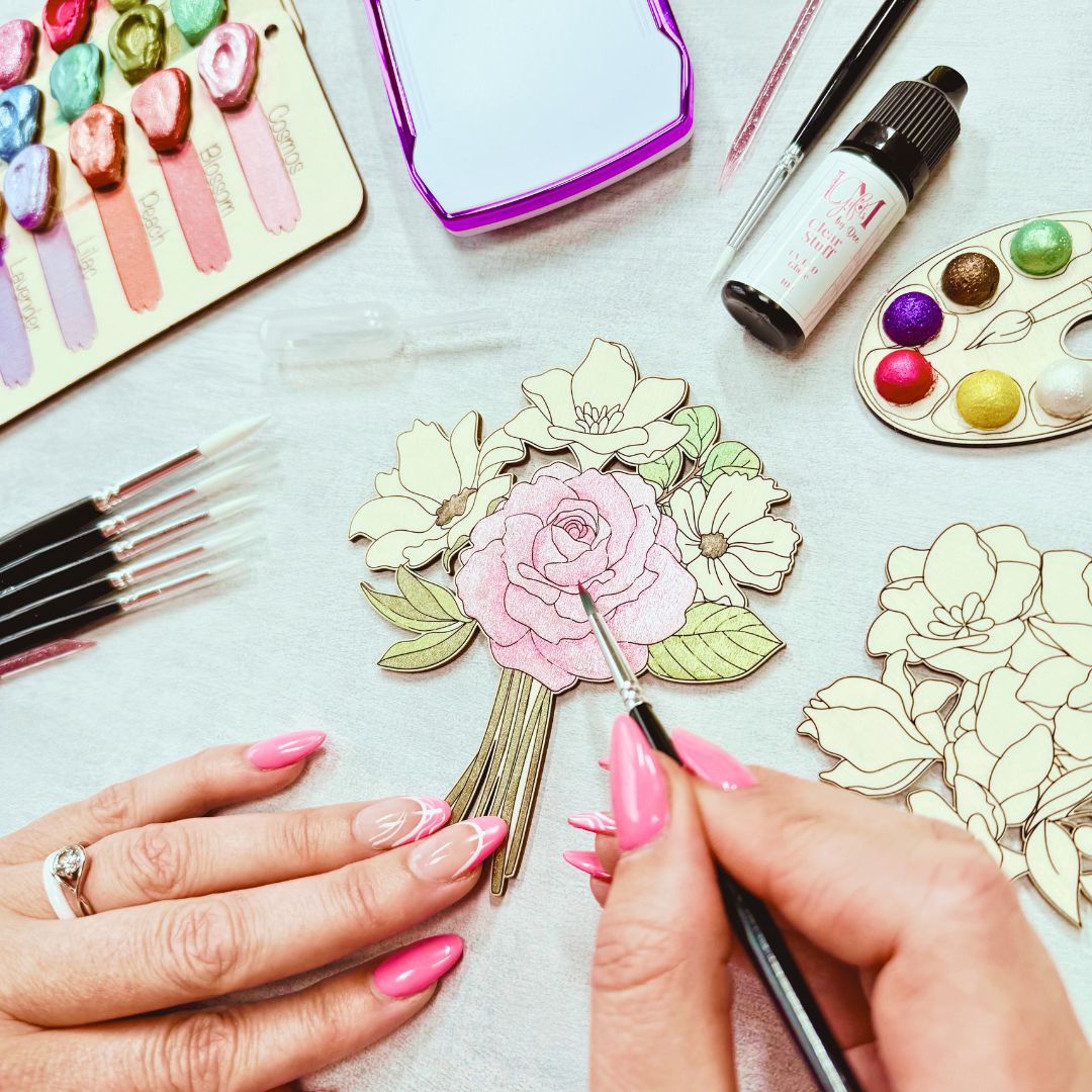 Hands painting wooden floral design from adult craft kit using shimmer watercolour paints